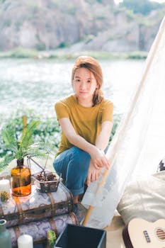 一位年轻女子坐在宁静的湖边，四周绿植环绕，享受着夏日的休闲时光