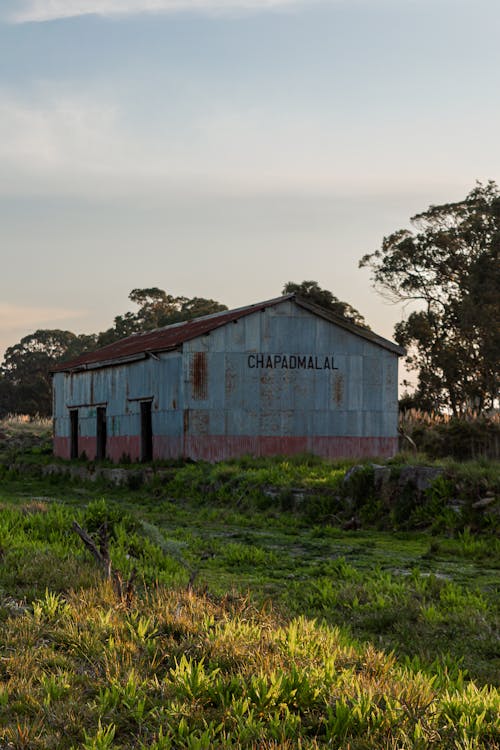 An Old Barn on Green Grass Under a Blue Sky