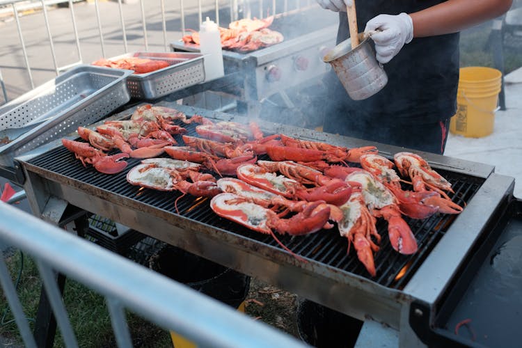 Person Cooking Lobsters On A Grill