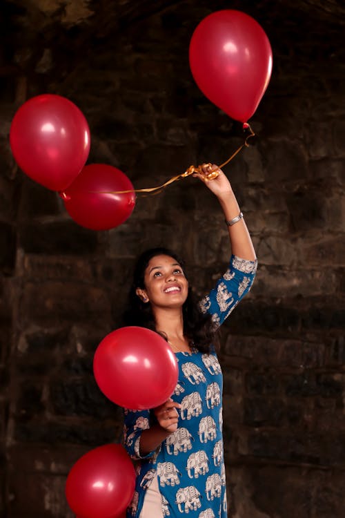 Vrouw Met Rode Opblaasbare Ballonnen Permanent In De Buurt Van Bakstenen Muur