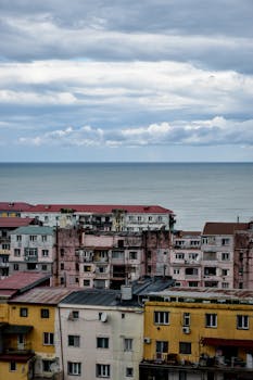 View of seaside urban buildings under a cloudy sky, capturing the contrast between city life and nature.