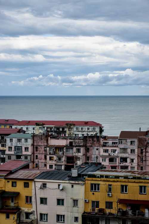Free View of seaside urban buildings under a cloudy sky, capturing the contrast between city life and nature. Stock Photo