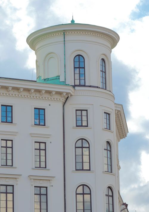 Free White concrete building with arched windows and a round tower against a cloudy sky. Stock Photo