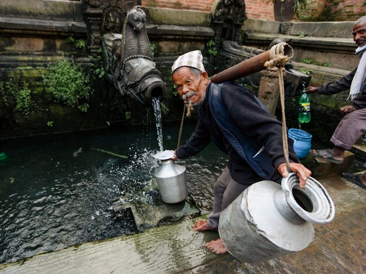 A Man Filling Up Jars With Water