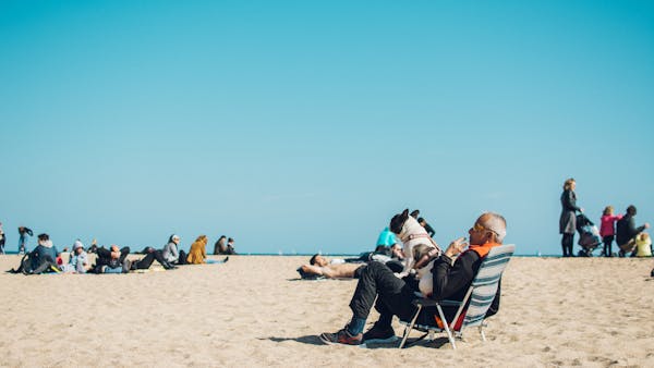 Elderly man with dog enjoying a sunny day at the beach in Barcelona, Spain.