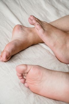 A relaxing scene of a couple's bare feet lying together on a bed, conveying intimacy and relaxation.
