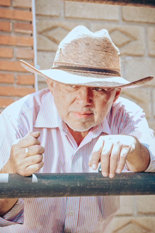 Free Elderly man leaning on a metal railing wearing a straw hat and striped shirt in Mexico. Stock Photo