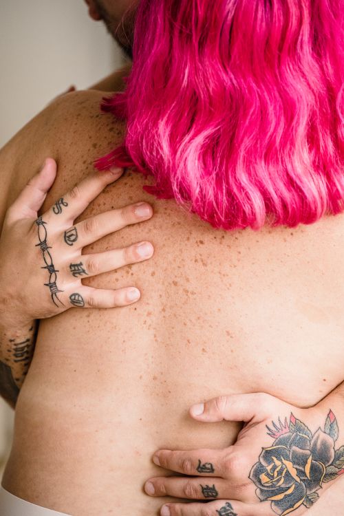 Free Intimate embrace of a tattooed couple, focus on tattoos and vibrant pink hair. Stock Photo