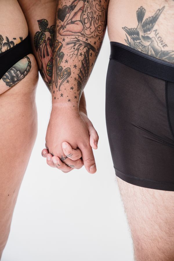 Zbliżenie na wytatuowaną parę trzymającą się za ręce