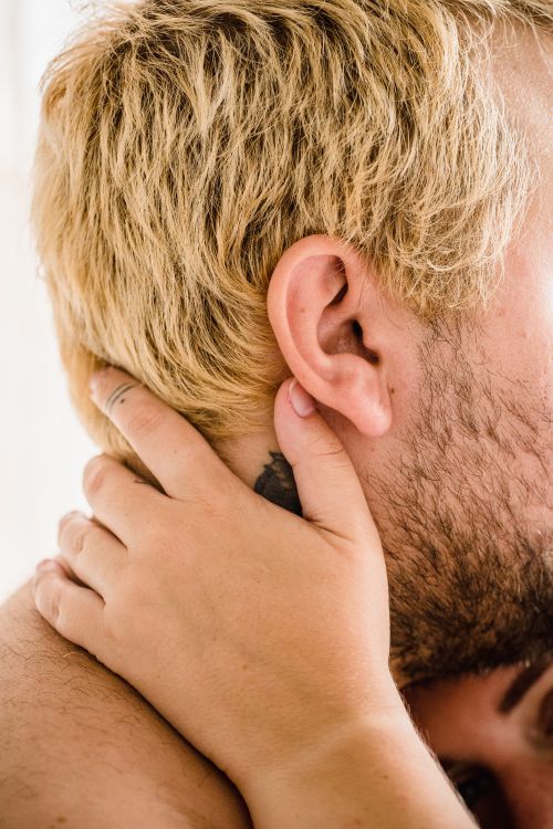 Free Tender embrace featuring a blonde man with a woman's hand touching his neck, expressing intimacy. Stock Photo