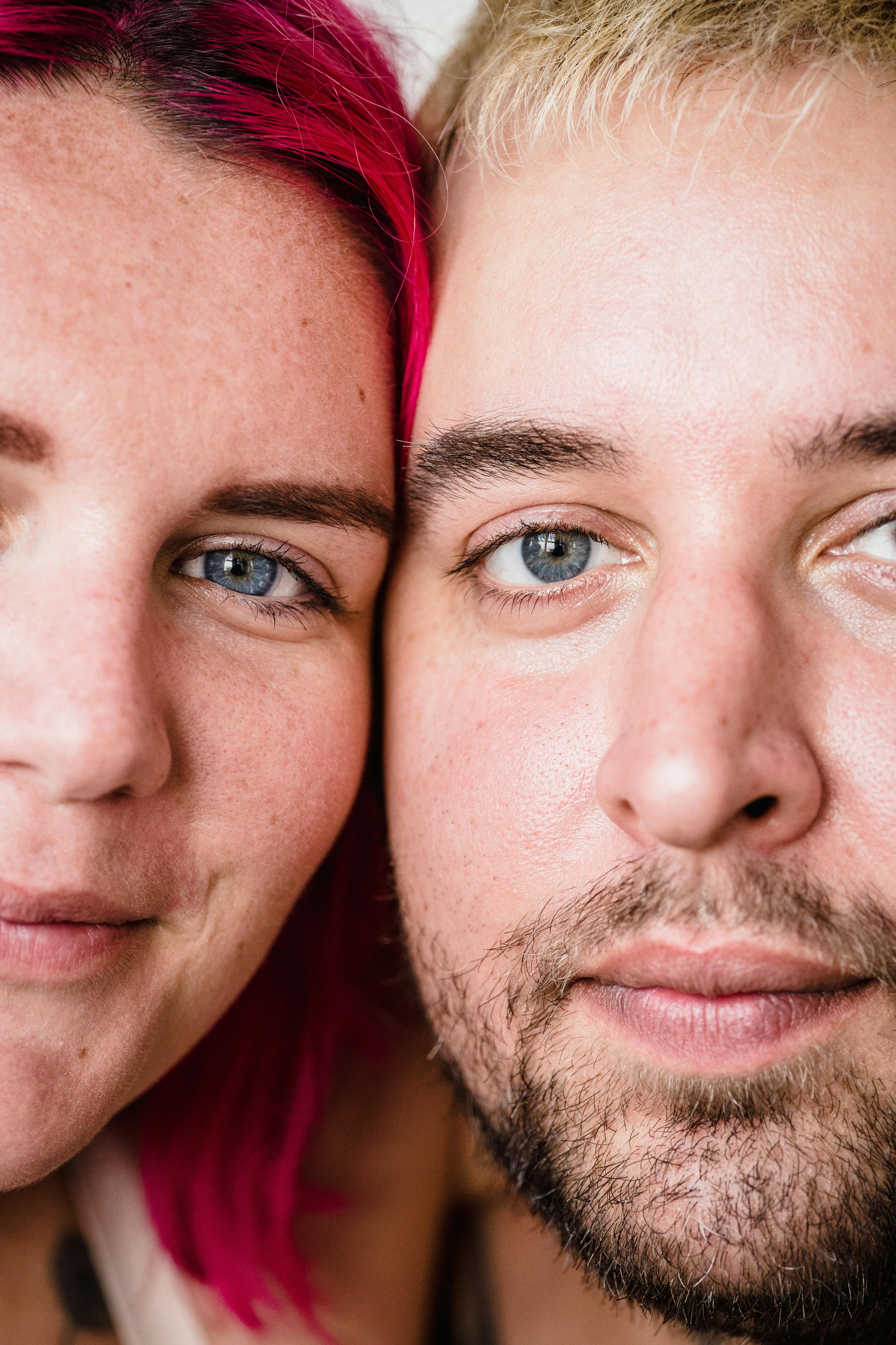 Intimate close-up portrait of a couple featuring vibrant pink and blonde hair.