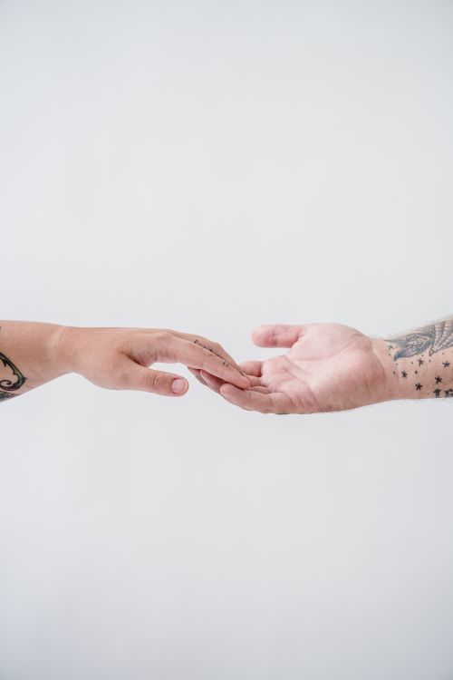 Free Two tattooed hands reaching towards each other against a white background, symbolizing connection. Stock Photo