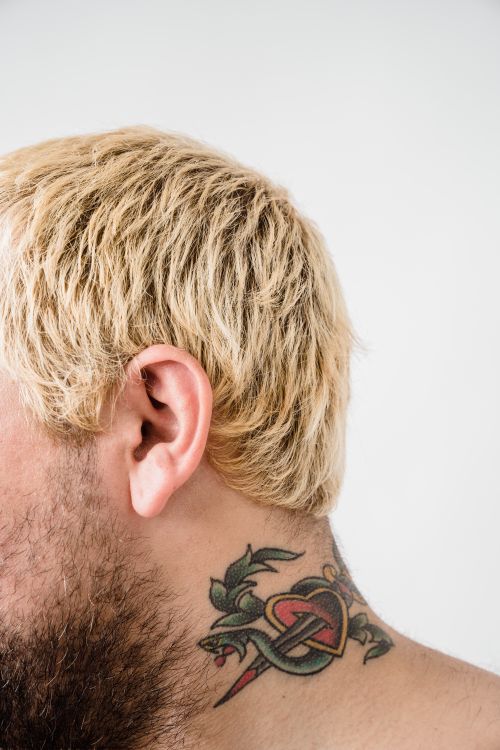 Free A close-up view of a colorful tattoo on a blonde man's neck against a white background. Stock Photo