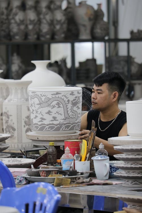 Man Painting a Ceramic Pot in an Art Studio 