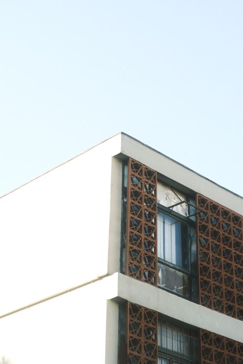 Free Close-up of a modern building facade featuring geometric patterns against a blue sky. Stock Photo