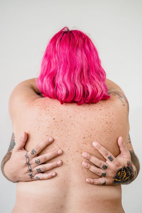Free A close-up of a couple embracing, showcasing tattoos and vibrant pink hair. Stock Photo