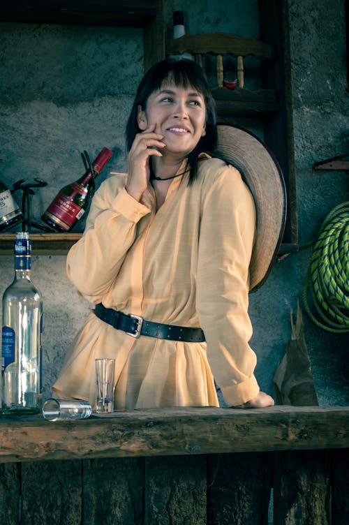 Woman in Yellow Long Sleeve Shirt Standing Beside the Wooden Counter