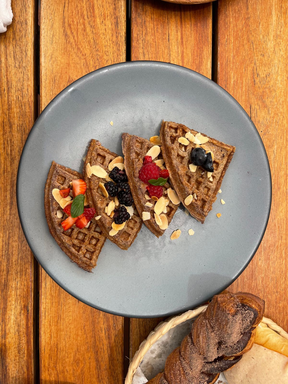 Waffles topped with berries and almonds on a gray plate