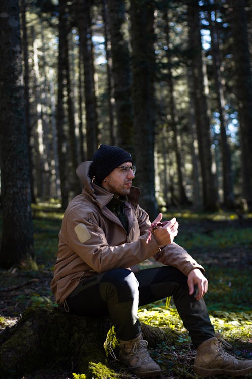 Man Sitting on Log in a Forest 