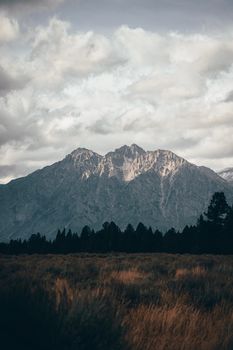 Breathtaking mountain range with snow-covered peaks under cloudy sky.