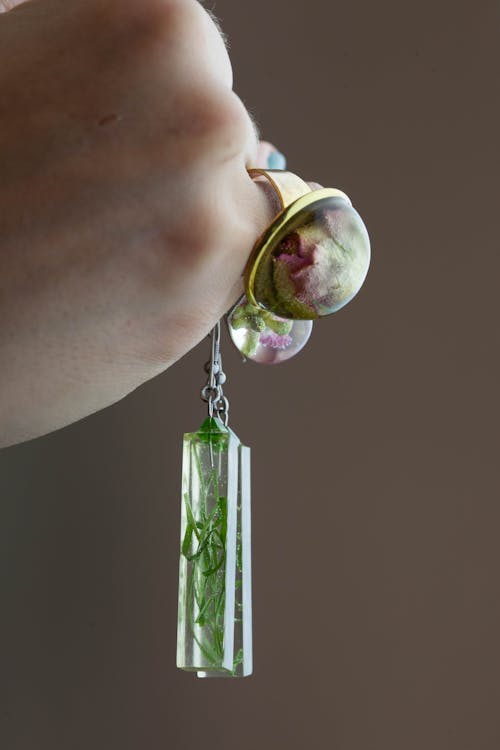 免费 拿着矩形绿叶镇纸吊坠时戴金色花泡泡戒指的人 素材图片