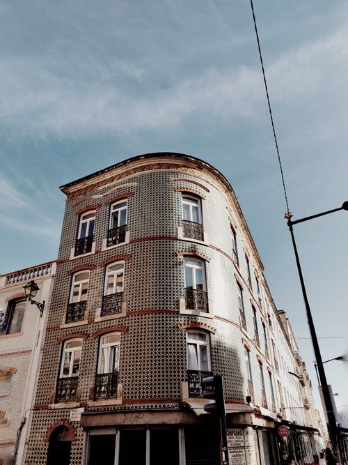 Free Elegant urban building with a patterned tiled facade under a clear blue sky. Stock Photo