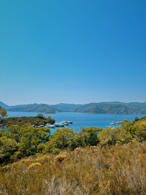 Free A stunning aerial perspective of a tranquil harbor surrounded by lush greenery and tranquil waters under a clear blue sky. Stock Photo