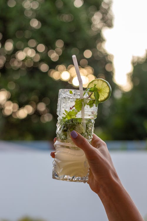 Person Holding a Clear Glass of Drink