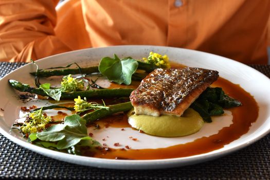 Delicious grilled fish served with asparagus and colorful sauce. Perfect for gourmet dining in Cape Town.