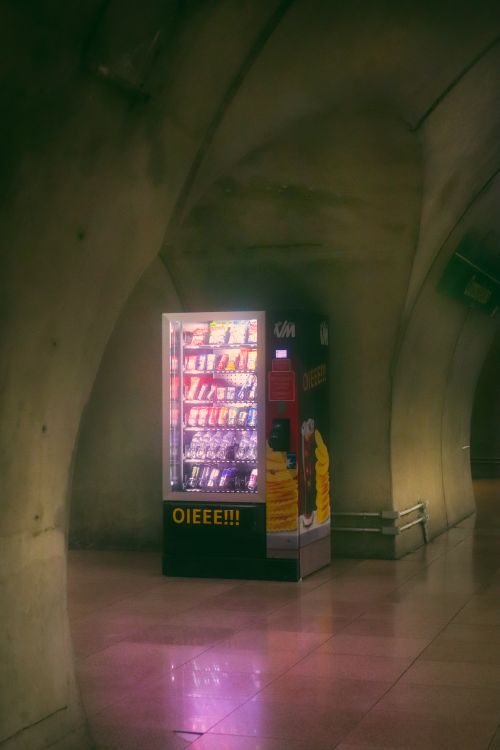 Free A brightly lit vending machine in an underground corridor with arched walls. Stock Photo