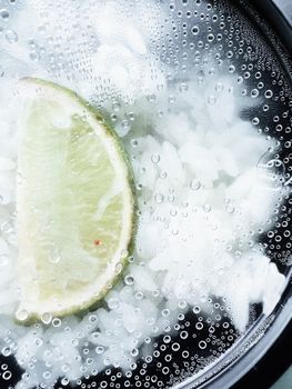 A close-up view of a lime slice on steamed rice with water droplets, creating a fresh look.