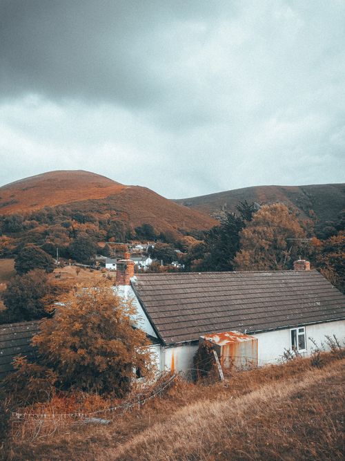 Free Picturesque countryside bungalow nestled among rolling hills during autumn. Stock Photo