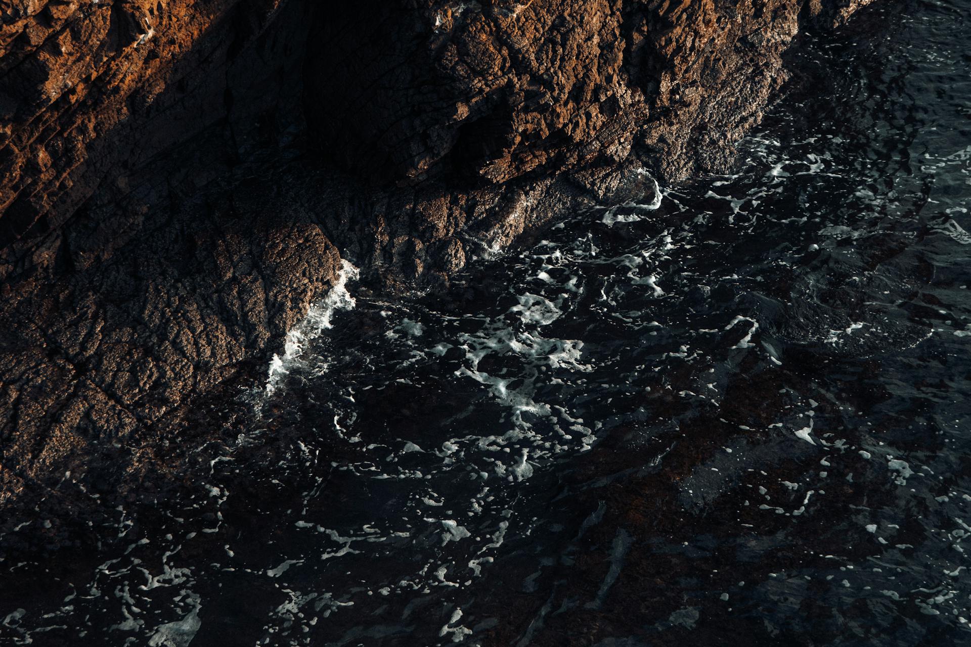 A striking image of rough coastal rock formations meeting the churning ocean waves.