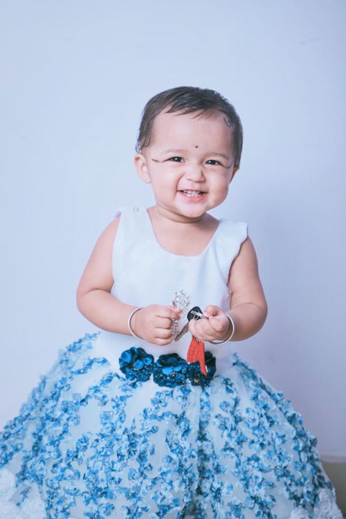 Free Charming baby girl in a blue dress smiles brightly, showcasing pure joy and innocence. Stock Photo