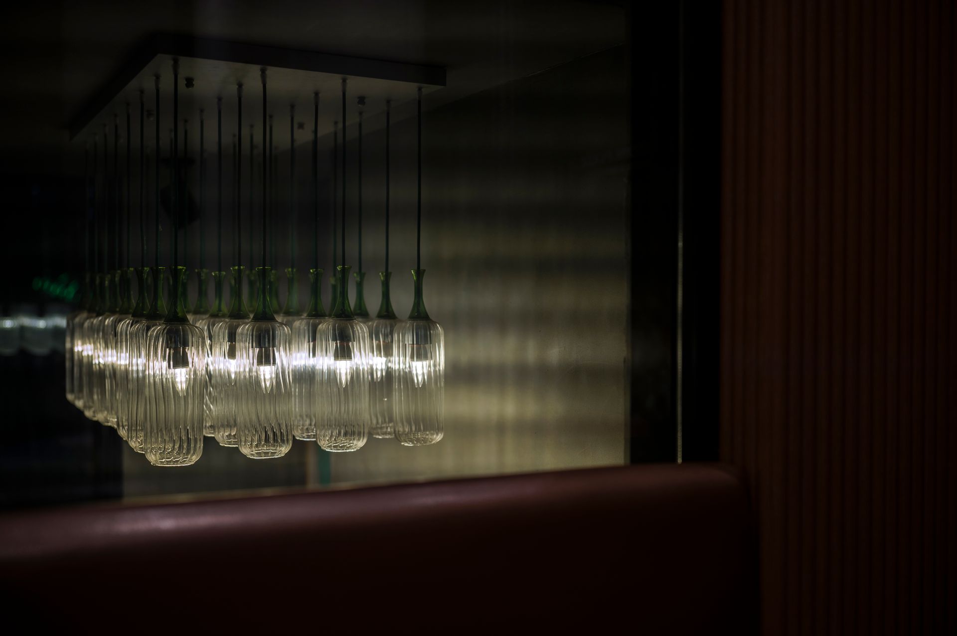 Artistic view of illuminated pendant lights reflecting on glass in a chic interior.