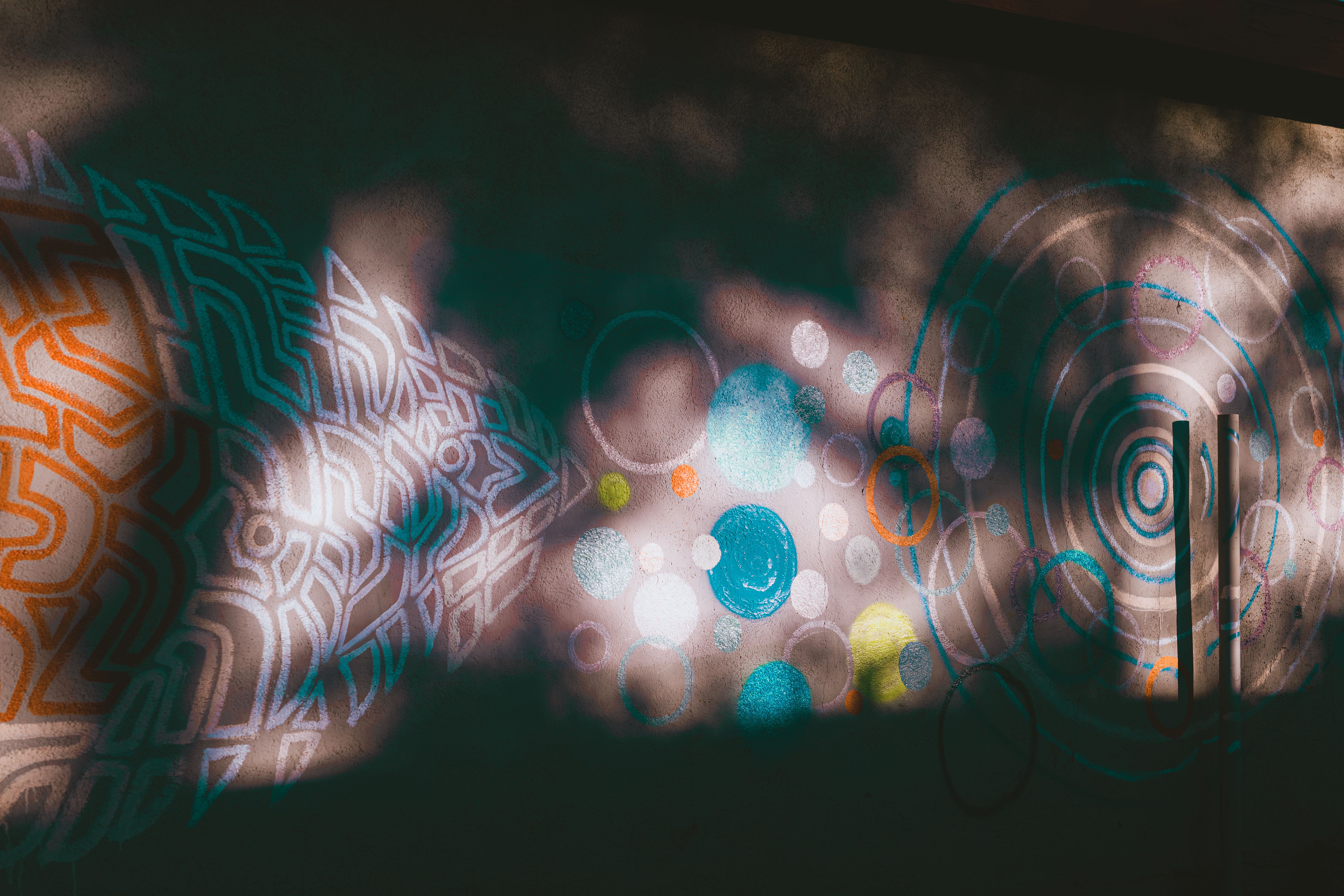 Vibrant graffiti with abstract shapes and patterns on a sunlit urban wall.