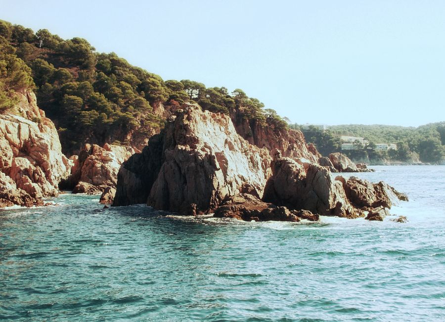 Dramatic rocky cliffs meeting the azure sea in Costa Brava, Spain. Ideal summer escape.