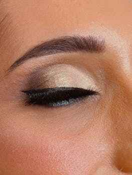 A detailed shot of glamorous eye makeup with closed eye, showcasing shimmering eyeshadow and eyeliner.
