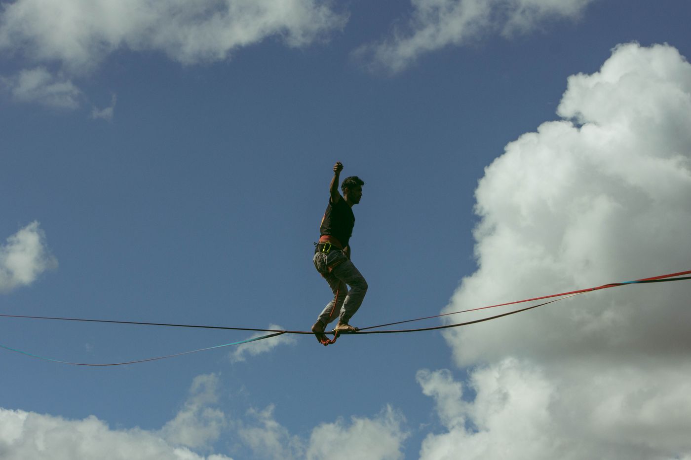 Mann balanciert auf einer Slackline unter blauem Himmel