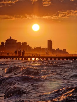 Silhouetted people admiring a sunset over Jesolo's skyline, Italy, creating a dramatic coastal scene.