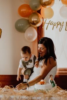 A joyful moment between mother and child during a birthday celebration indoors, with balloons and cake.