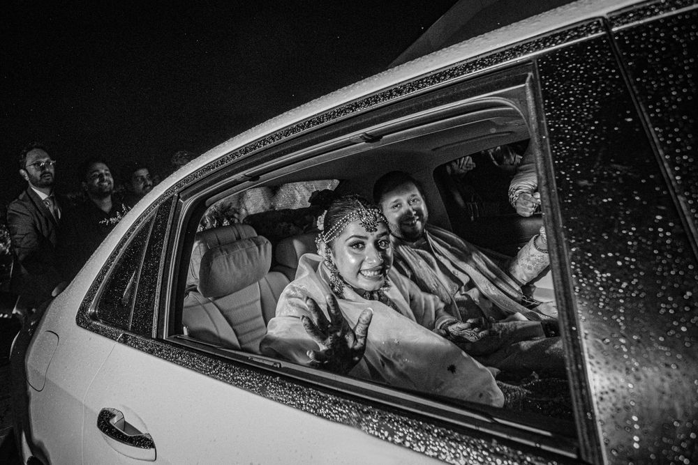 Bride and groom smiling from a car during their wedding
