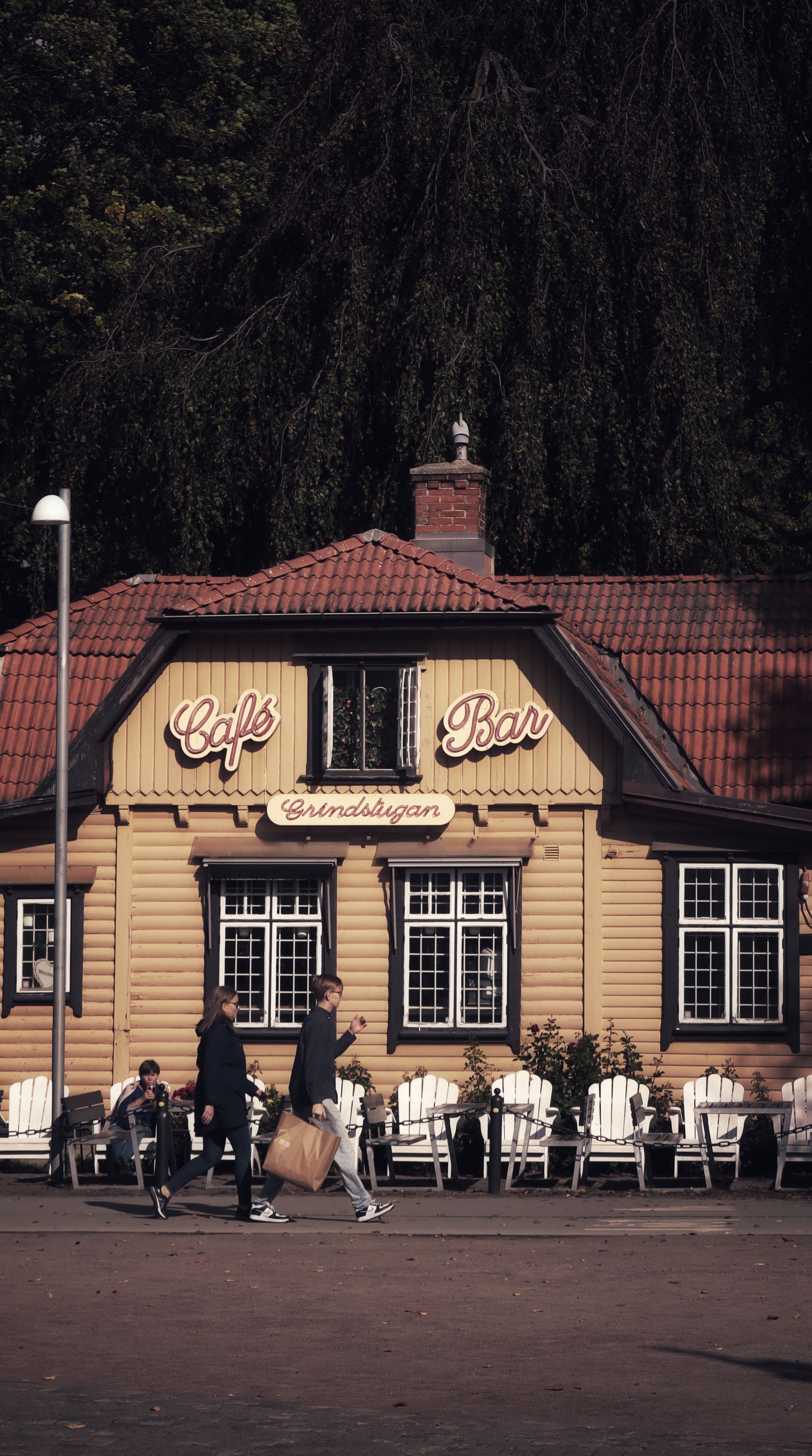 A quaint café bar with people walking outside, showcasing a cozy outdoor setting.