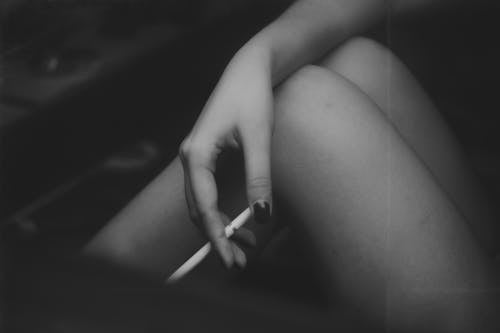 Grayscale Photo of Person Holding Cigarette Stick