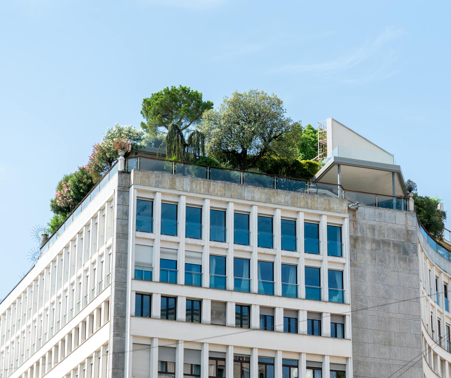 A modern building featuring lush rooftop gardens under a clear blue sky.