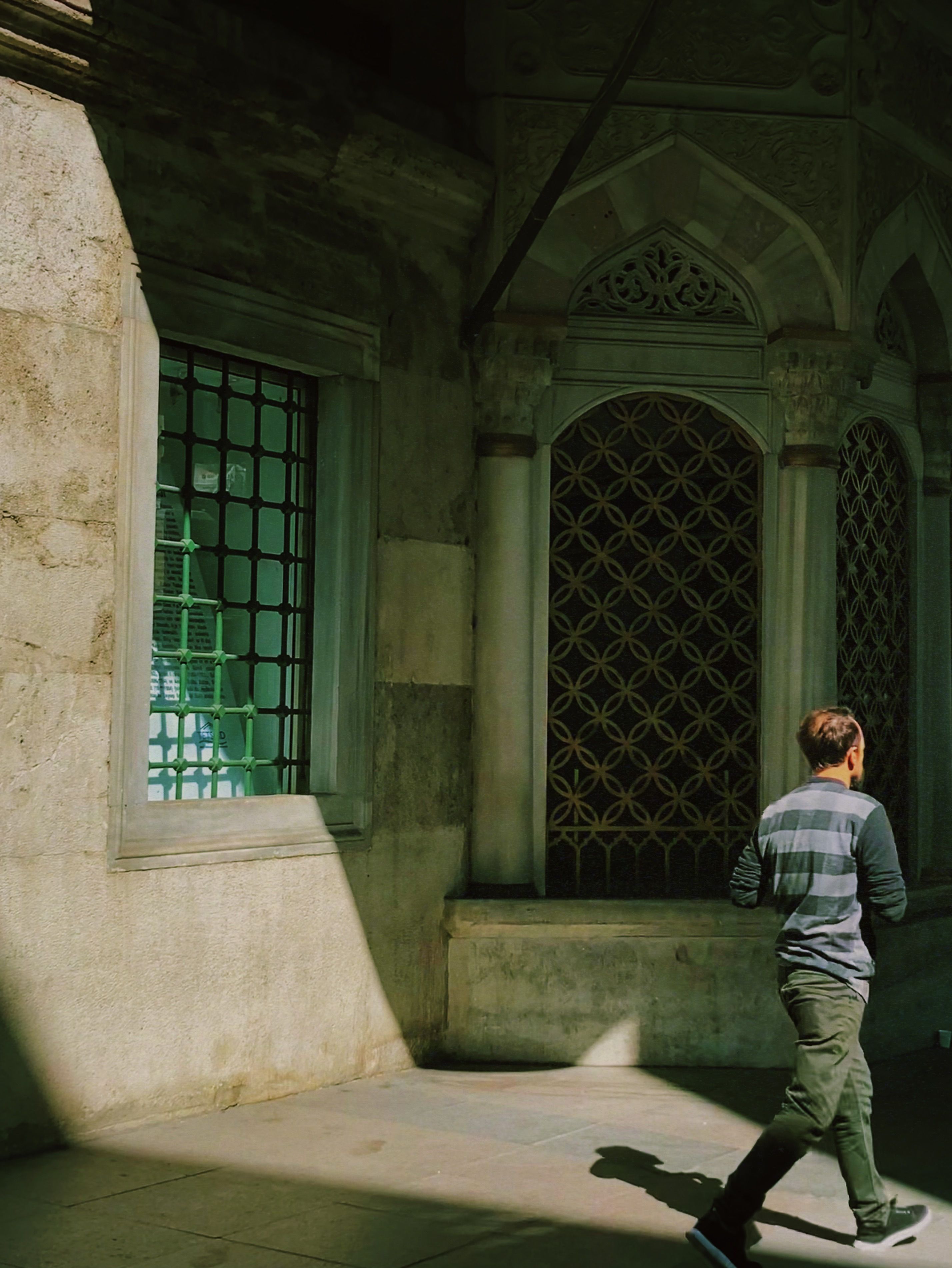 Back View Shot of a Man Walking Outside an Old Building · Free Stock Photo