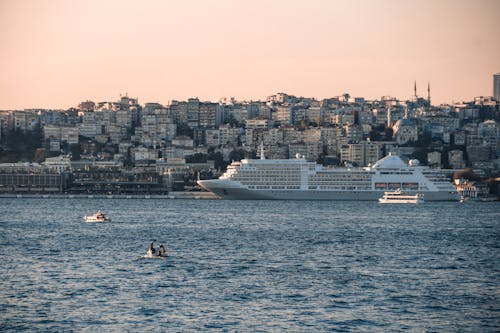 Ferry  and Cruise Ship Sailing on the Sea Near City Buildings