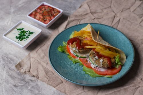 Free Delicious vegetarian wrap with fresh vegetables and sauces, perfect for a vibrant meal. Stock Photo
