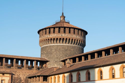 Free View of Sforzesco Castle's iconic fortification tower under a clear blue sky in Milan, Italy. Stock Photo