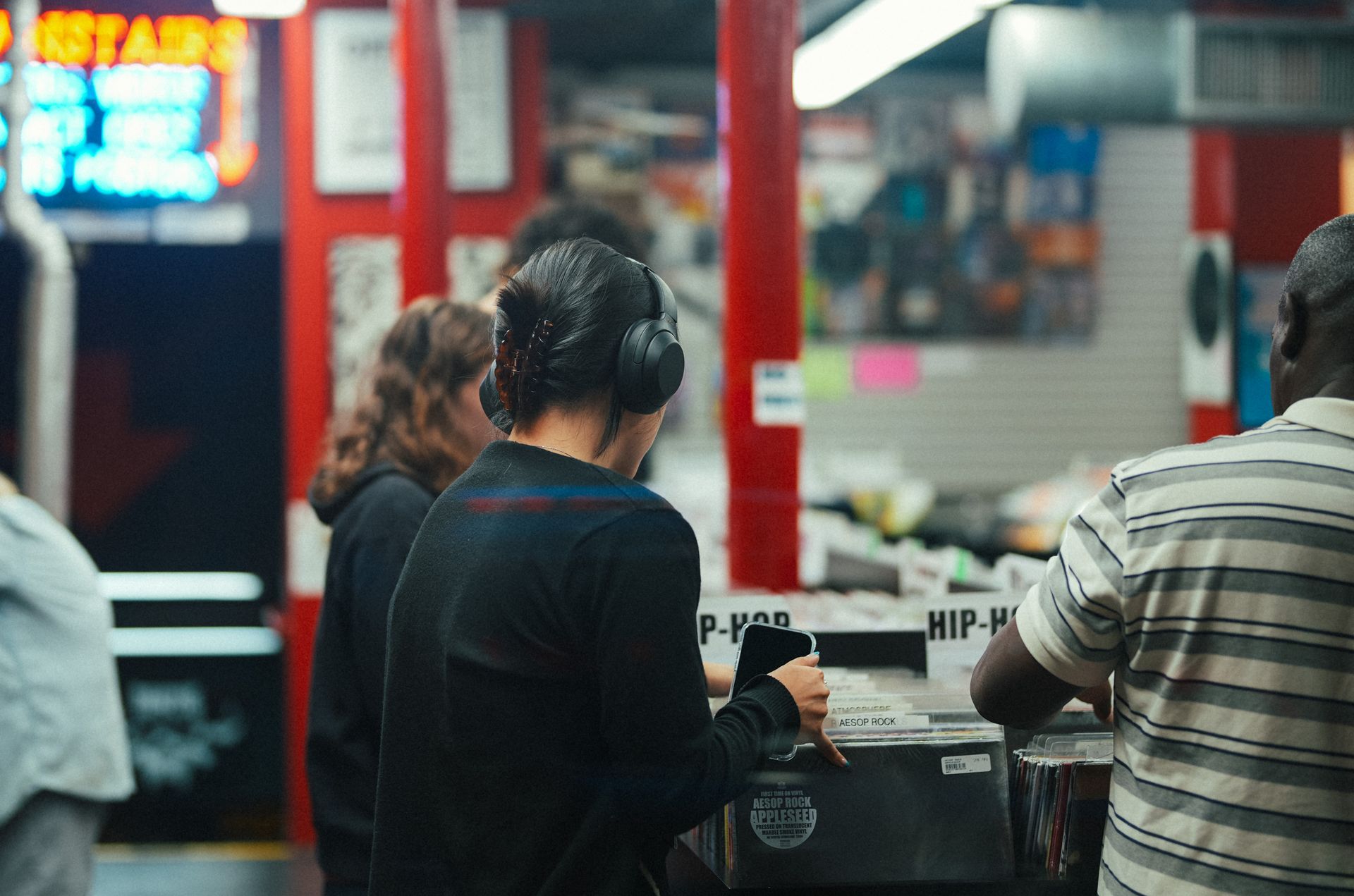 People exploring vinyl records in a bustling music store with vibrant atmosphere.